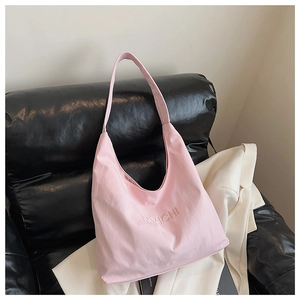 Close-up of pink tote bag with MVICHI letter embroidery on a stylish black sofa