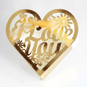 Macro detail of golden heart gift box with I Love You laser cut patterns and gold ribbon