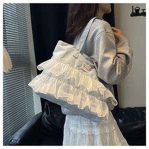 Close-up of light blue denim tote bag with white lace ruffles and Fashion Bag label