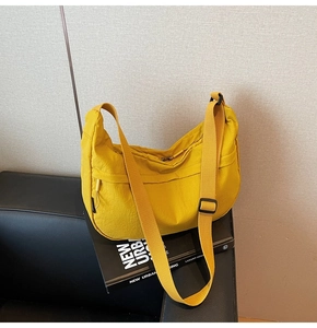 Détail d'un sac bandoulière croissant en nylon jaune vif avec une large bandoulière