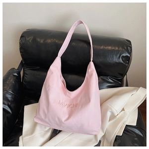 Pink tote bag detail with MVICHI letter embroidery on soft fabric over leather sofa