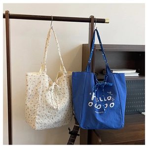 Detail of floral and solid canvas tote bags hanging on a wooden rack in a cozy room