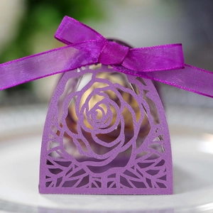 Macro della scatola di caramelle rosa tagliata al laser con un fiocco di nastro viola