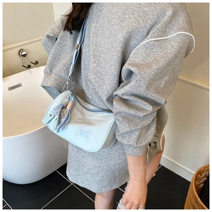 Detail of light blue semi-circular shoulder bag with embossed logo and woven strap