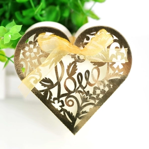 Close-up of golden heart-shaped metal candy box with hollow LOVE design and organza ribbon