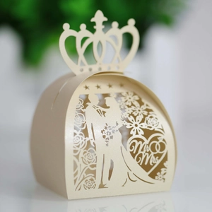 Macro shot of cream laser-cut wedding favor box with crown top and Mr & Mrs heart detail