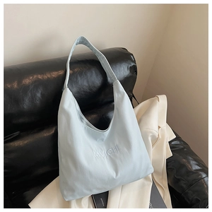 Macro shot of light blue canvas tote bag with white letter embroidery on black sofa