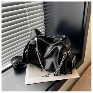 Close-up of shiny black leather shoulder bag with silver chunky chain and metal eyelets