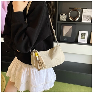 Detail of beige crescent bag with CHUU text and adjustable strap on stylish model