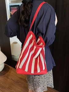 Sac fourre-tout en maille rayée rouge et blanc avec anses en cuir porté par un mannequin