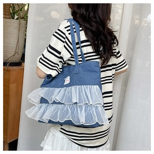 Detail of blue denim tote bag with white organza ruffles and lace side decoration