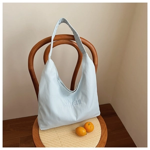 Detail of light blue hobo tote bag featuring exquisite MVICHI letter embroidery on fabric
