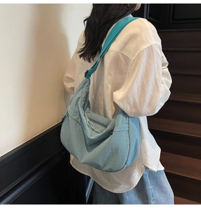 Gros plan d'un sac demi-lune en nylon bleu clair porté par un mannequin