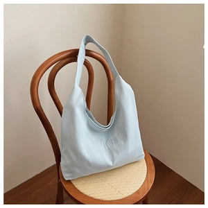 Detailed view of light blue canvas tote bag hanging on a wooden wicker chair