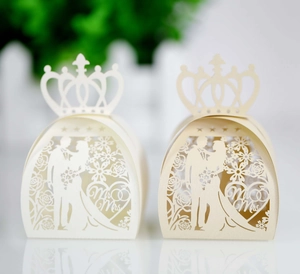 Close-up of laser-cut wedding candy boxes with crown top and Mr & Mrs silhouette details