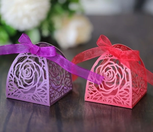 Dettaglio di motivi a rosa tagliati al laser su scatole di caramelle nuziali rosa e viola