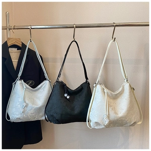 Detailed close-up of embroidered shoulder bags with drawstrings in three colors