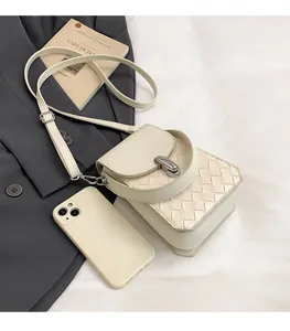 Detail of a beige woven crossbody bag with a metallic buckle on grey suit background