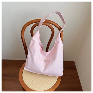 Detail shot of pink tote bag with MVICHI logo embroidery on minimalist woven chair