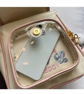 Detail of a beige PU leather backpack featuring a clear PVC front pocket for smartphones