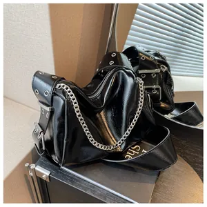 Detail of black glossy patent leather crossbody bag with chunky silver chains and eyelets
