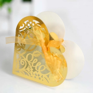 Close-up of golden heart-shaped laser-cut favor box with Love text and satin ribbon