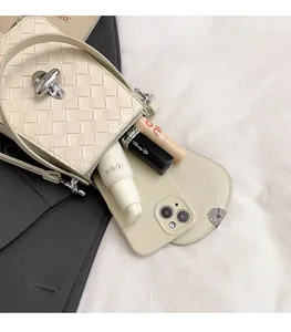 Detail view of the interior capacity and woven texture of the off-white mini crossbody bag