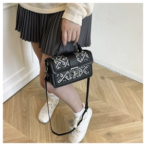Detail of a vintage square bag with black white embroidery and silver metal twist lock