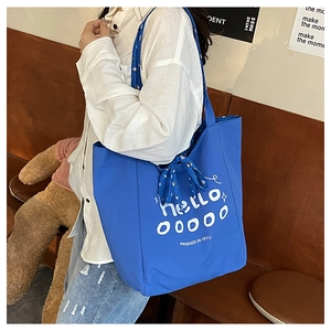 Sac fourre-tout en toile bleue avec foulard floral porté par un mannequin en café