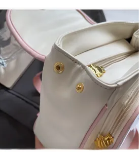 Detail of pink edged cream leather backpack with gold hardware and custom zipper pulls