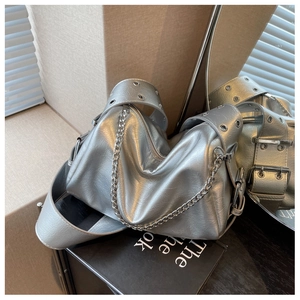 Detailed close-up of a silver textured pillow bag featuring a bold metal chain and eyelets