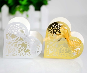 Close-up of laser-cut heart favor box with Love calligraphy and silk ribbon bow