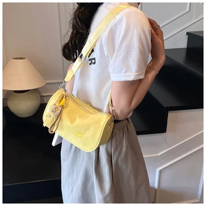 Side view of bright yellow nylon crossbody pillow bag with wide adjustable shoulder strap