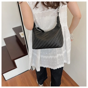 Close-up of black woven shoulder bag with herringbone texture and silver metallic buckle