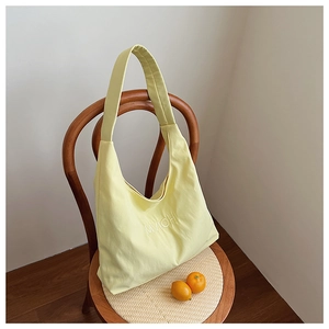 Detail of light yellow quilted tote bag hanging on a chair in a lifestyle setting