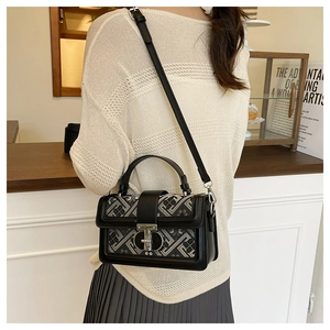 Detail of a geometric fabric shoulder bag with a black leather flap and metal clasp
