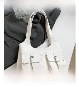 Detail view of white faux leather underarm bag featuring two pockets with silver buckles