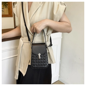 Detail of a black crossbody phone bag with quilted texture and silver metallic clasp
