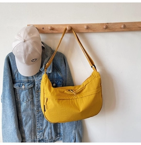Sac bandoulière demi-lune en nylon jaune accroché avec une tenue décontractée de style