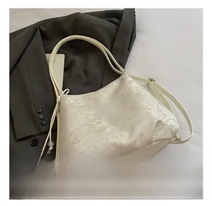 Close-up of cream white shoulder bag with floral jacquard texture and drawstring detail