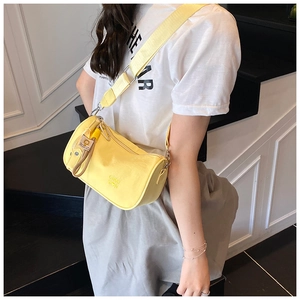 Detail of a bright yellow nylon cylinder crossbody bag featuring a branded wide shoulder strap