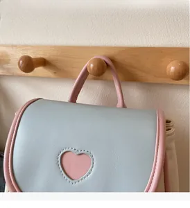 Detail of soft handle and pink heart patch on a light blue mini backpack for girls