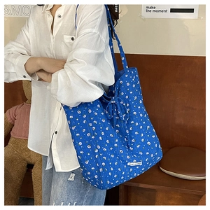 Détail d'un sac cabas en toile à fleurs bleues avec étiquette et ruban décoratif