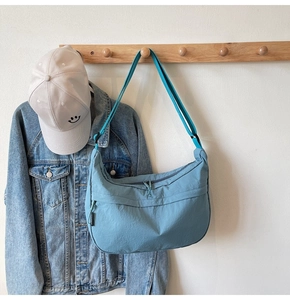 Détail du sac bandoulière bleu Morandi en nylon avec fermeture éclair double et étiquette tissée