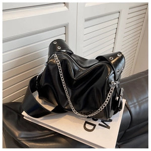 Close-up of shiny black pleated leather texture and silver chain strap on fashion bag