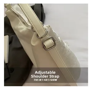 Detail view of the white shoulder bag featuring embossed floral texture and adjustable strap