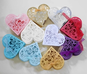 Close-up of laser-cut heart favor boxes with Love lettering and satin ribbons