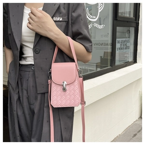 Detail of pink woven crossbody phone bag with silver metal clasp on model in grey suit