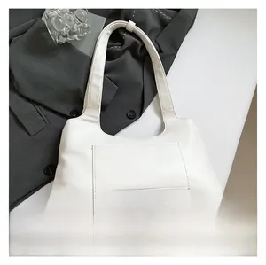 Detail view of white leather shoulder bag with functional front pocket and wide strap