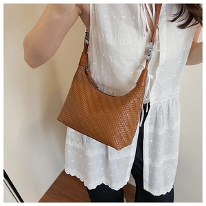 Detail of a brown woven crescent shoulder bag featuring a classic V-pattern texture